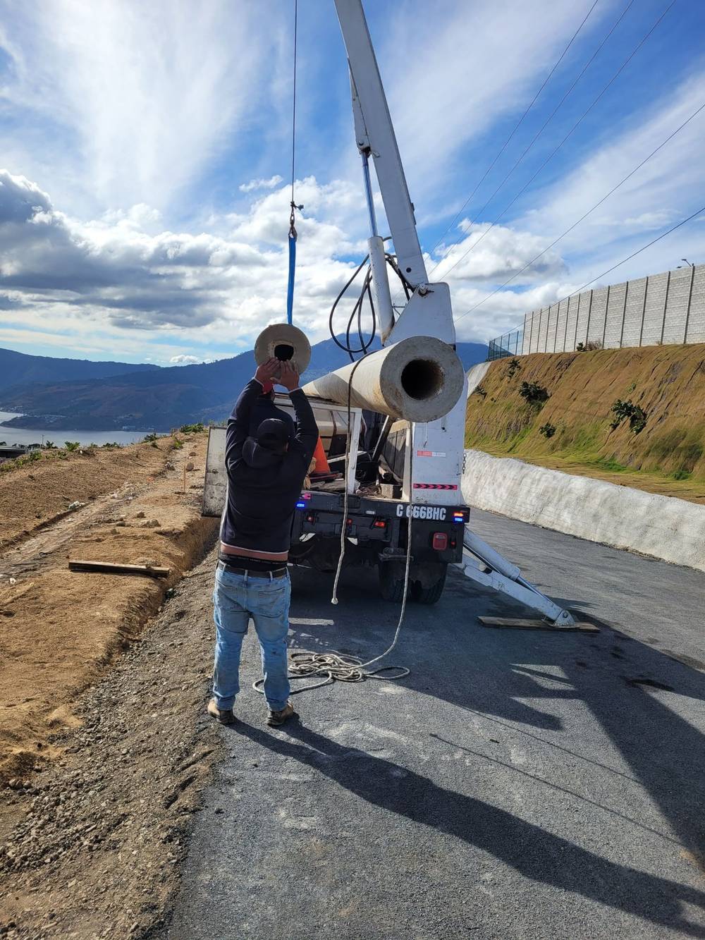 Cuadrilla descargando poste desde camión grúa