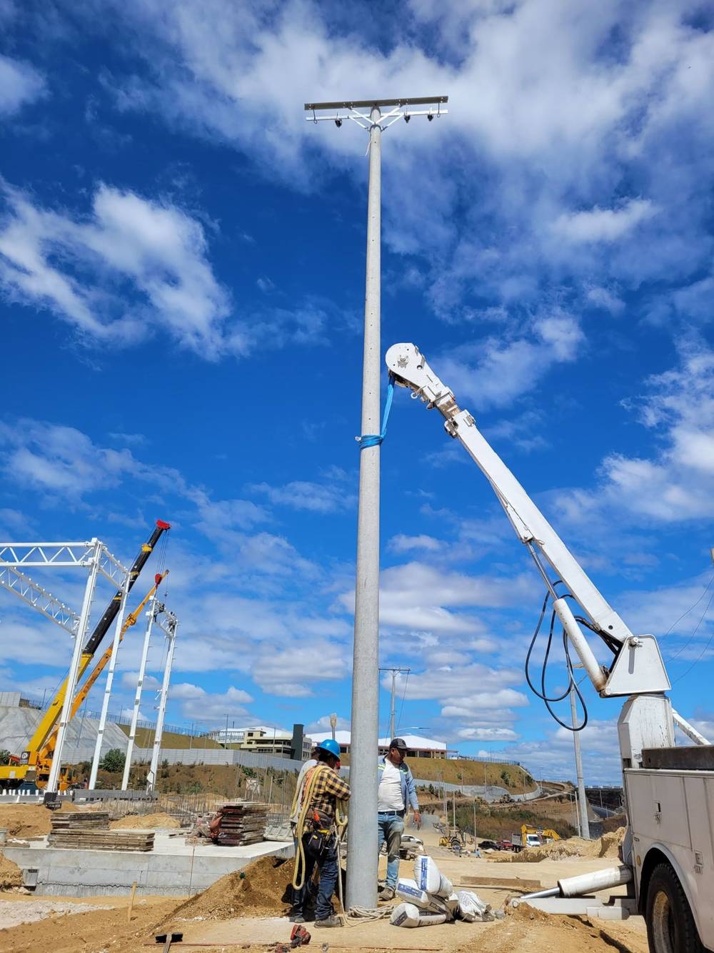 Grúa colocando un poste de media tensión bajo cielo azul