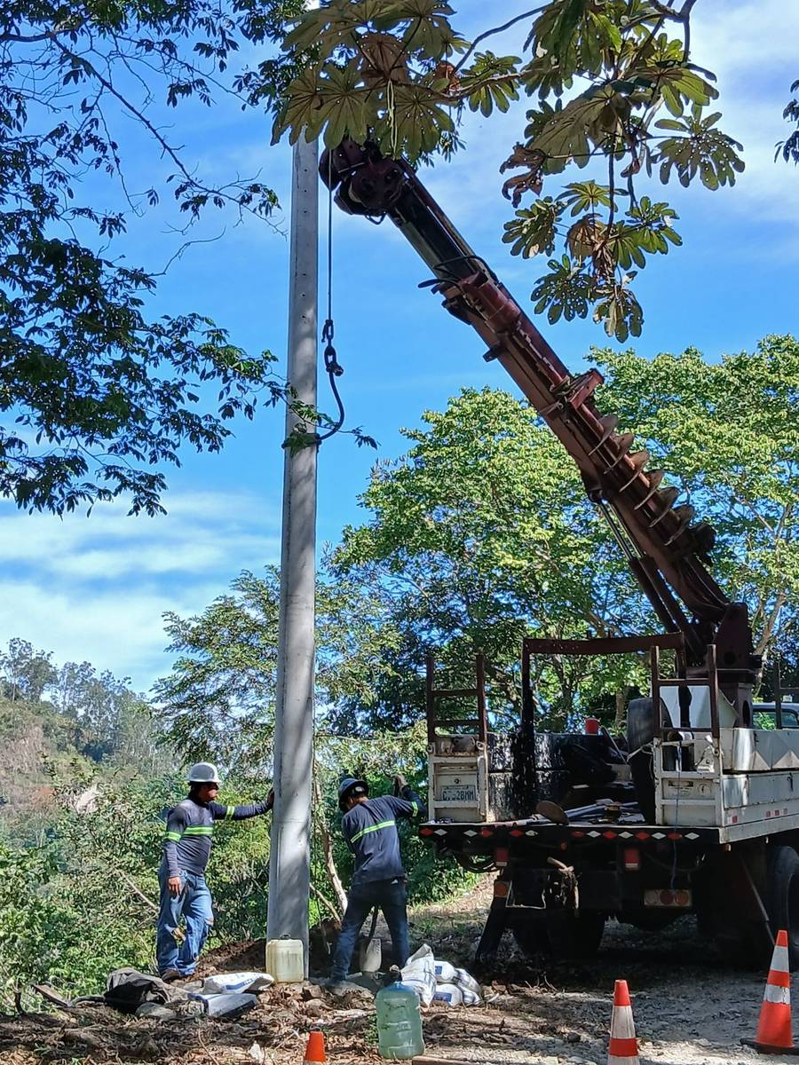 Cuadrilla de EISA instalando un poste de concreto con grúa